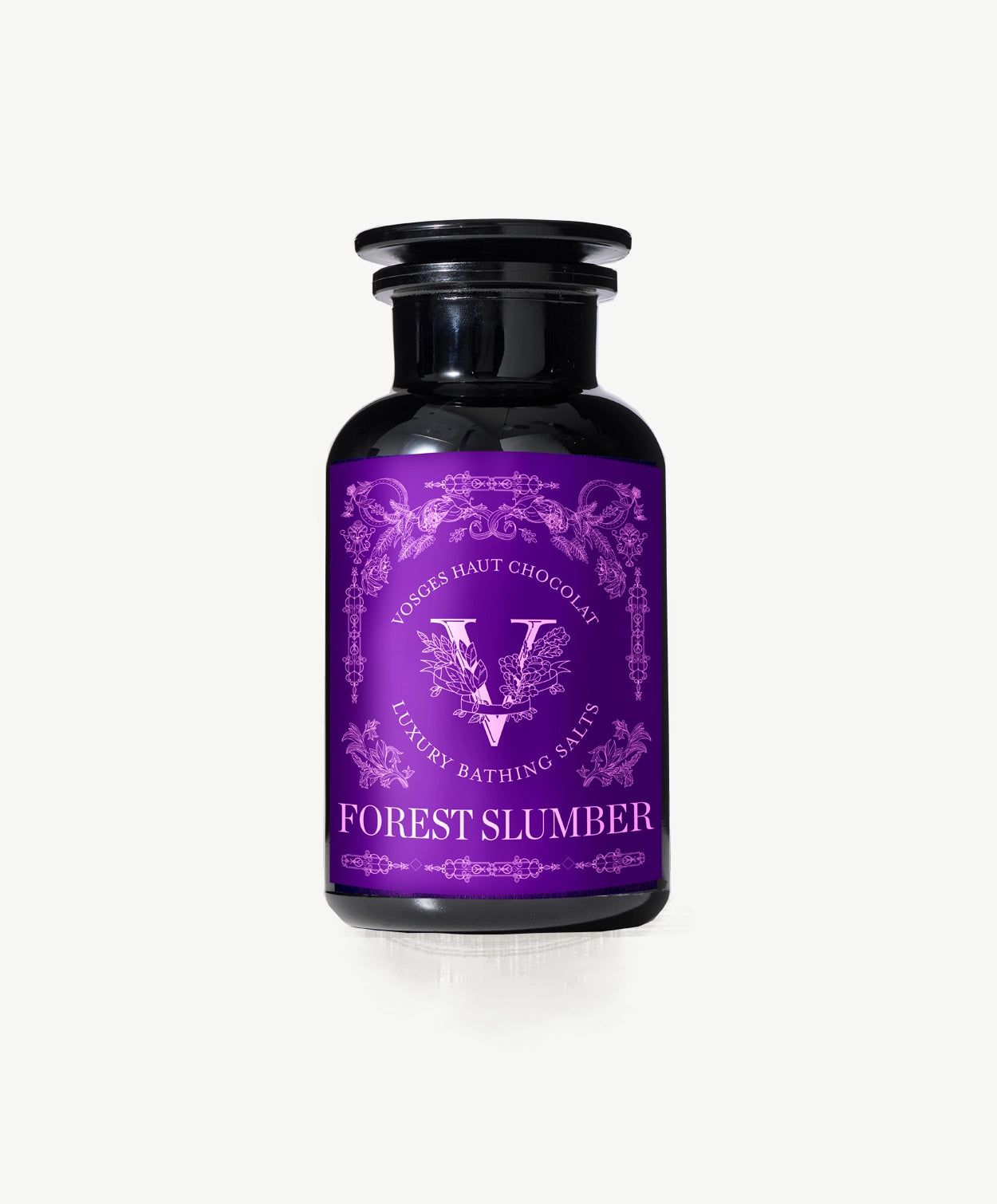 Vosges Haut Chocolat Forest Slumber bath salts in a dark glass jar with an ornately decorated purple label with serif font on a light grey background.