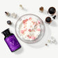 Vosges Haut Chocolat Forest Slumber bath salts beside several crystals and a bowl of flower petals on a light grey background.