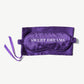 Vosges Haut Chocolat purple silk sleep mask on top a matching storage bag with a purple ribbon on a light grey background.