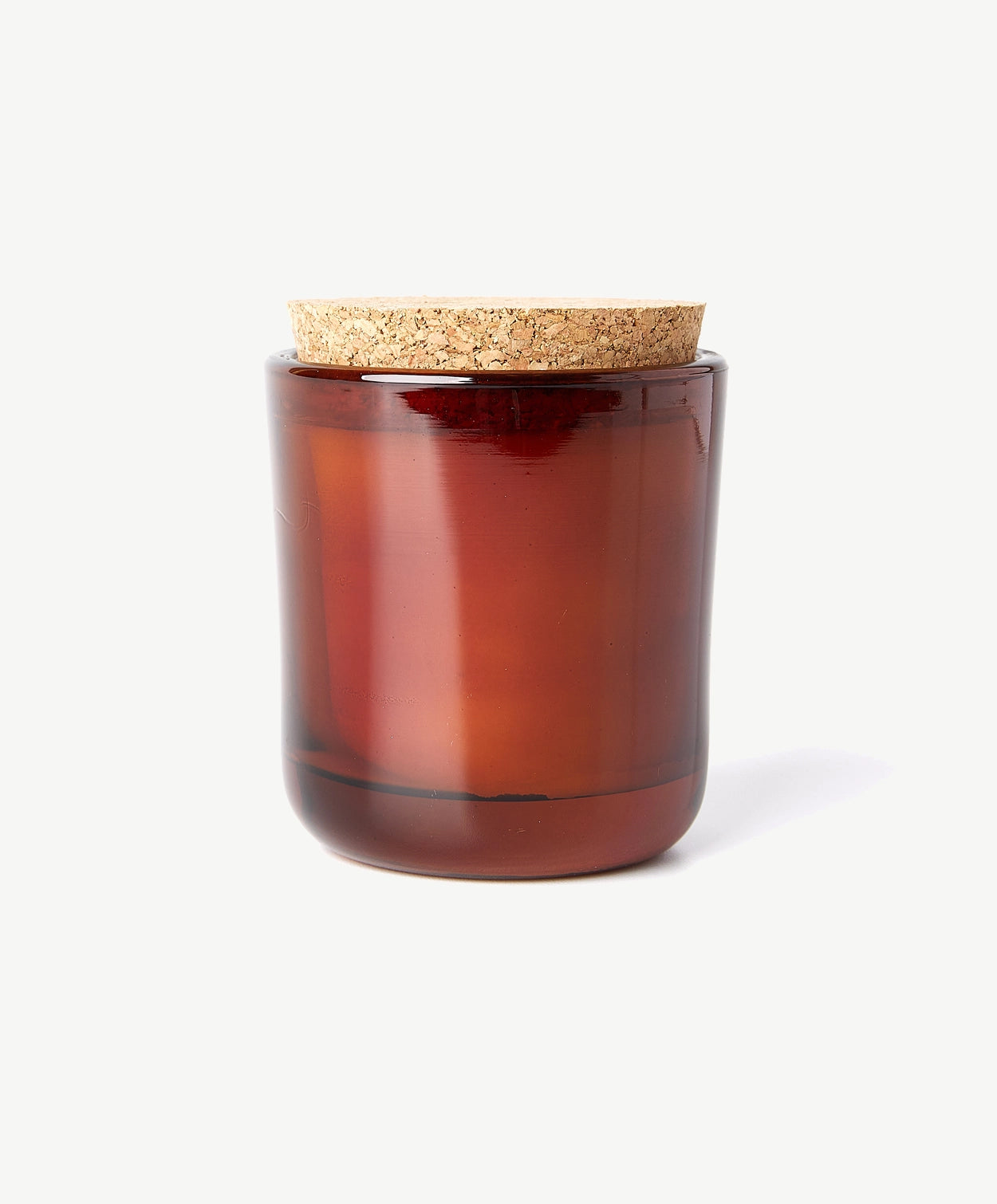 A deeply scented Linnea’s Lights candle in a brown glass jar topped with a natural cork lid sits on a white background.