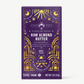 Vosges Raw Almond Butter Pure Plant chocolate bar stands upright in a dark purple box  decorated with golden suns and moons on a grey background.