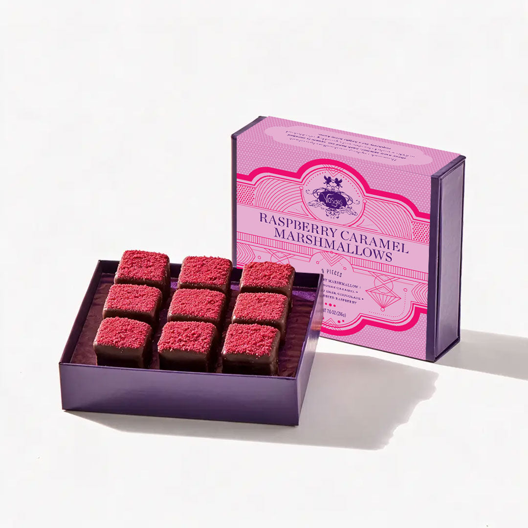 Open purple box reveals nine square chocolate marshmallows topped with pink sugar crystals.
