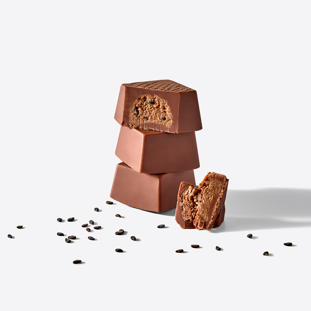 Three stacked milk chocolate blocks with a crumbly interior exposed and coffee beans scattered around.