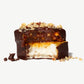 Close-up of a Vosges Caramel Marshmallow with a bite taken showing layers of Caramel, Marshmallow chopped walnuts and pecans on a white background.