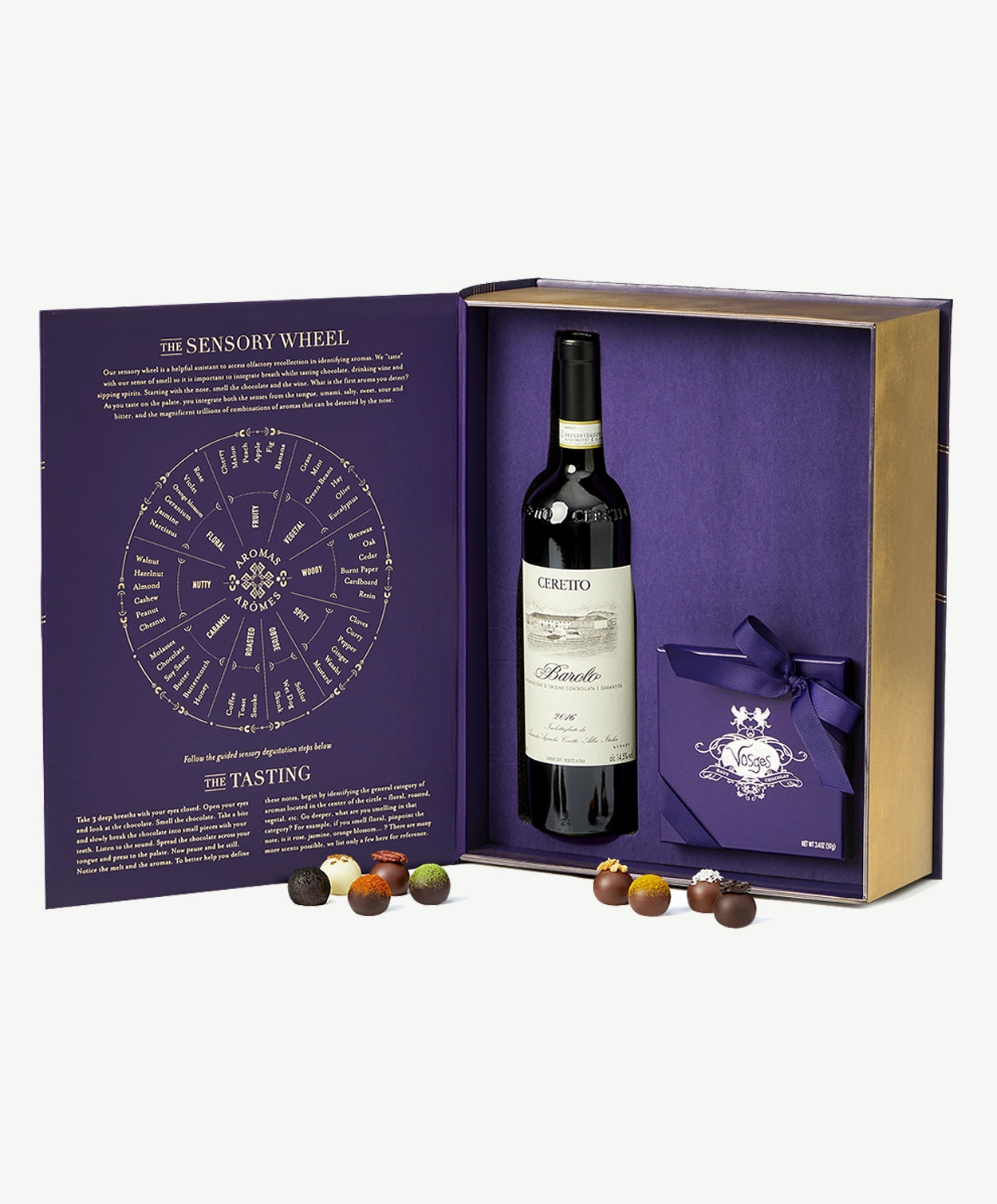 A large purple giftbox sits open revealing a bottle of Ceretto wine and a chocolate box tied with purple ribbon surrounded by several chocolate truffles on a grey background.