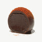 Vosges Haut-Chocolat Exotic Budapest Chocolate Truffle cut in half sprinkled with Kalocsan Paprika on a light grey background.