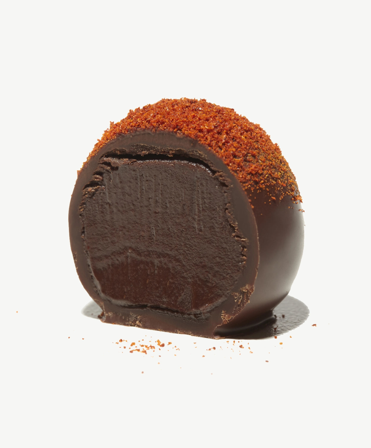 Vosges Haut-Chocolat Exotic Budapest Chocolate Truffle cut in half sprinkled with Kalocsan Paprika on a light grey background.