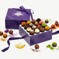 Open box of Vosges Haut-Chocolat surrounded by chocolate truffles and exotic ingredients on white background.