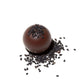 Glossy dark chocolate truffle topped with black sesame seeds on a white background