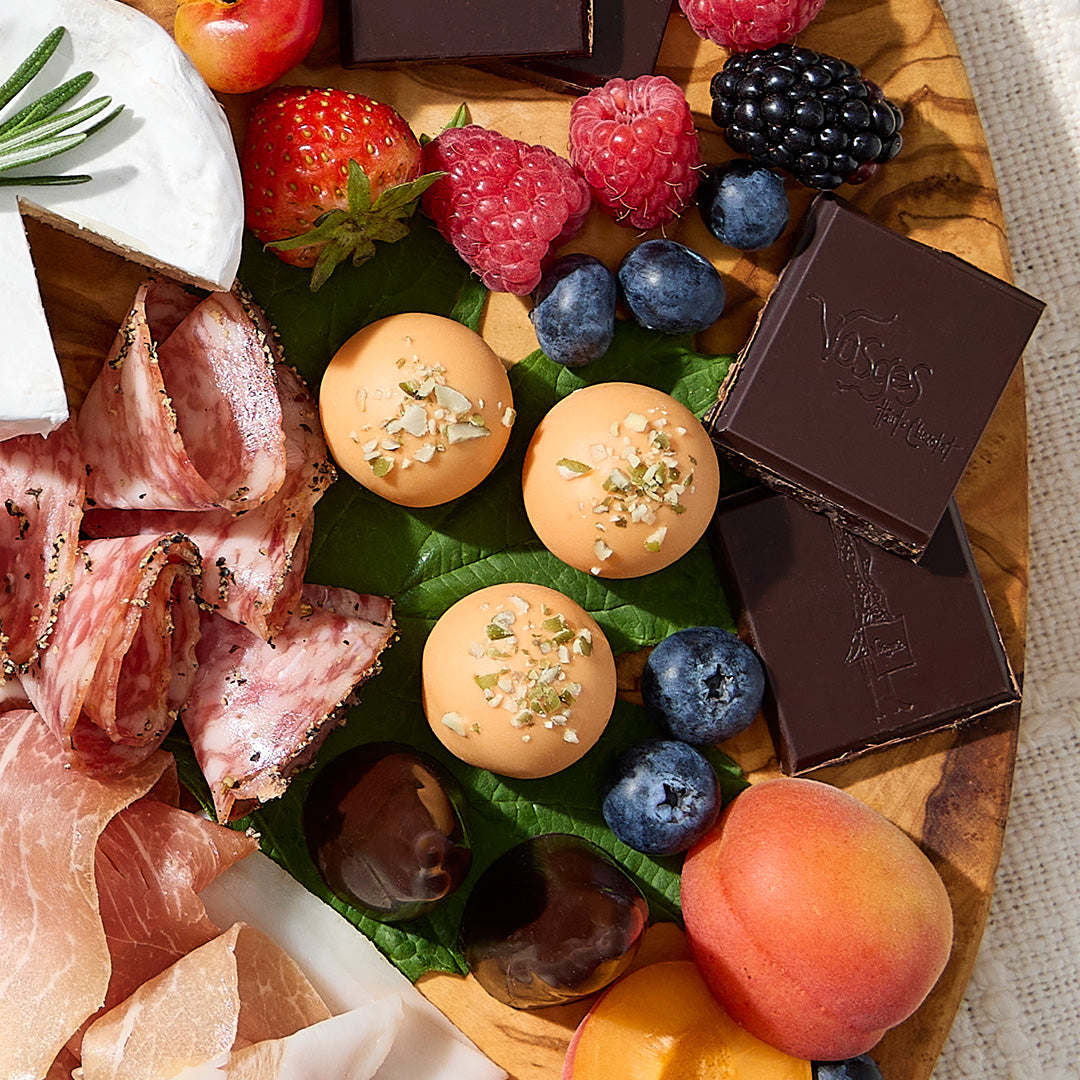 Assorted charcuterie board with meats cheese fruit and three pumpkin pie truffles among berries