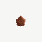 A close up of a Vosges Chocolate Maple Bomba Bite on a light grey background.
