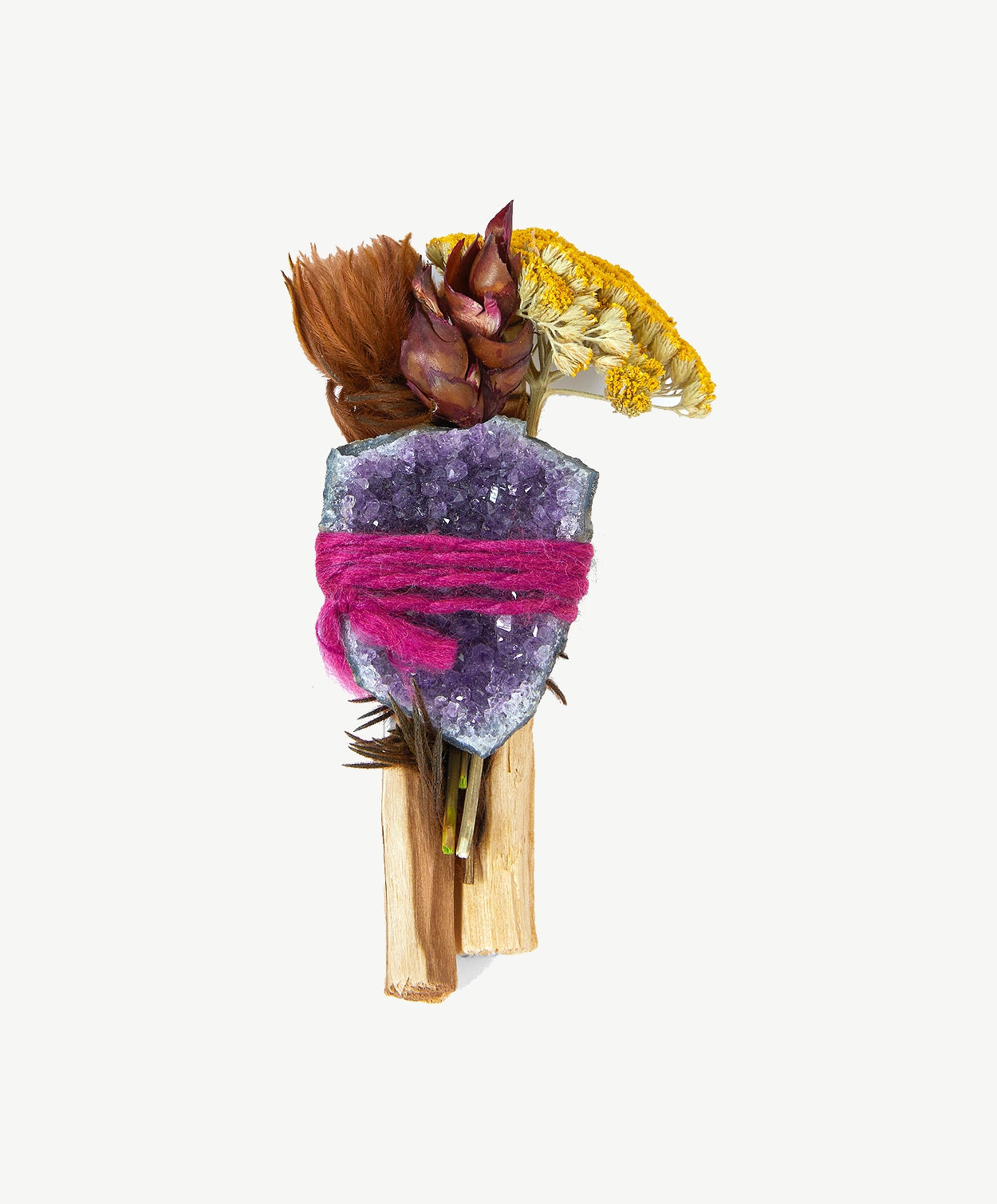 Palo Santo stick tied together with a purple crystal and dried flowers on a white background.
