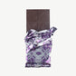 An opened Vosges Parmesan Walnut and Fig Chocolate bar in a silver wrapper stands upright on a white background.