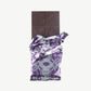 An opened Vosges Raw Honey Cacao Chocolate bar in a silver wrapper stands upright on a white background.