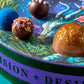 Closeup of four truffles in a Vosges candy box, adorned with brightly colored toppings and parfums.
