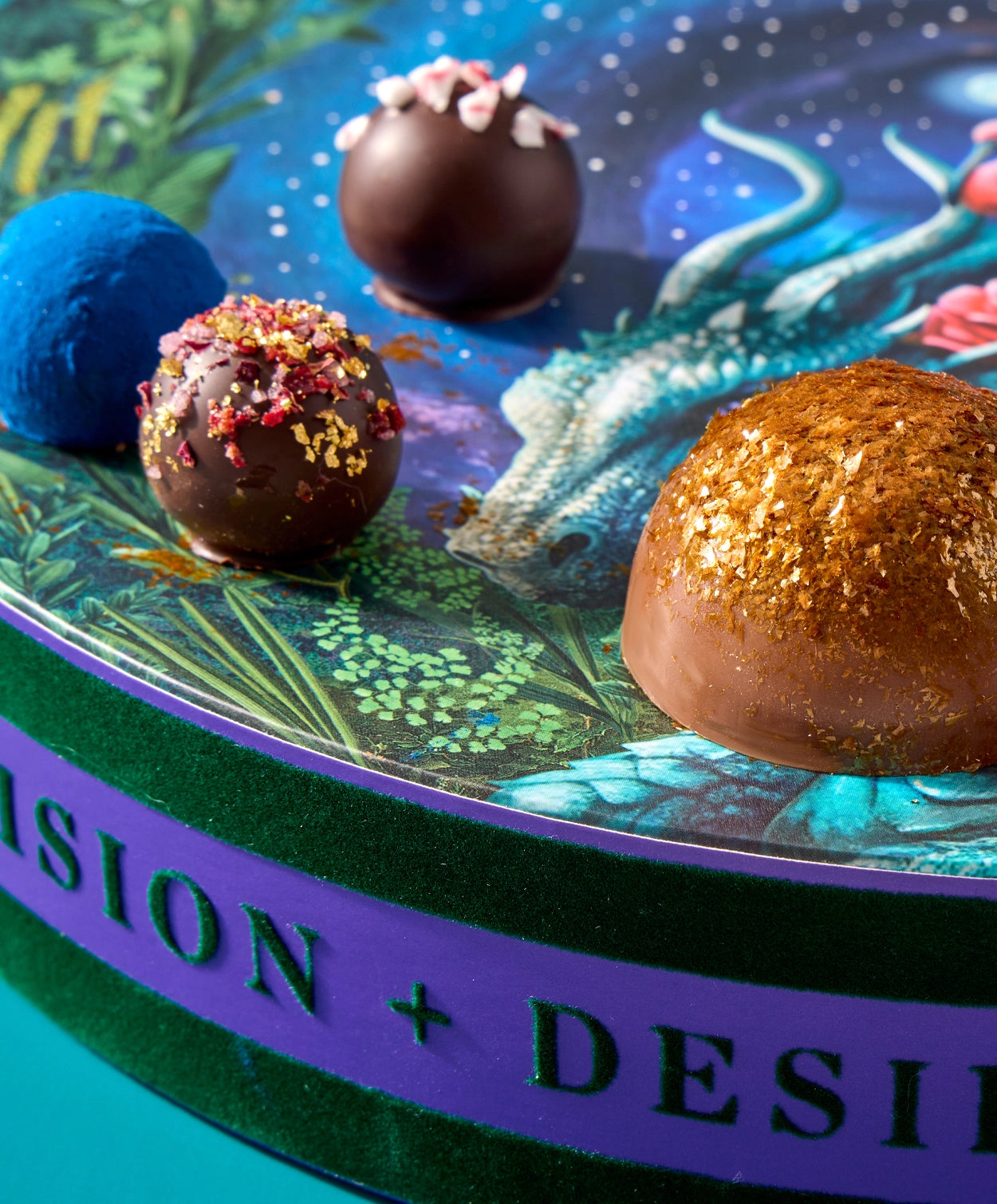 Closeup of four truffles in a Vosges candy box, adorned with brightly colored toppings and parfums.