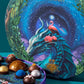 A closeup view of the Vosges Visionary collection artwork, ,a large blue dragon and pink egret sitting in a lush leafy forest infront a swirling night sky full of stars.
