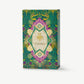 A green and purple Vosges toffee box adorned in gold foil stands upright on a light grey background.