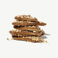 Close-up stack of Vosges Caramel Toffee  coated in milk chocolate and crushed nuts on a white background.  