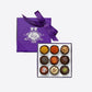 Purple Best of Vosges hatbox with a large purple ribbon and a box of chocolates partially visible.
