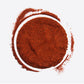 Pile of red chili powder with a curved arc on a white background