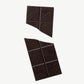 Vosges Mo's Dark Chocolate Bacon Bar broken in two on a light grey background.