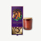 An opened Vosges chocolate box ornately decorated with a horse and gold foil sits open revealing peanut butter bon bons and a chocolate covered marshmallow beside a candle in a brown jar on a light grey background.