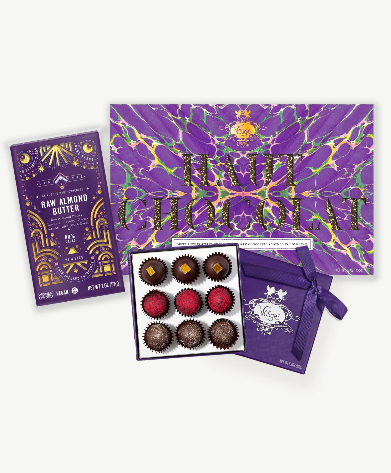 A large collection of Vosges Vegan Chocolate containing brightly colored truffles a raw almond butter bar and a 2 lb chocolate bar on a light grey background.