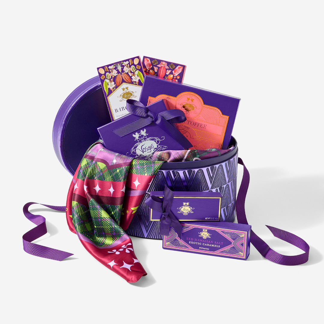Open purple Vosges hatbox filled with assorted chocolates and a colorful scarf
