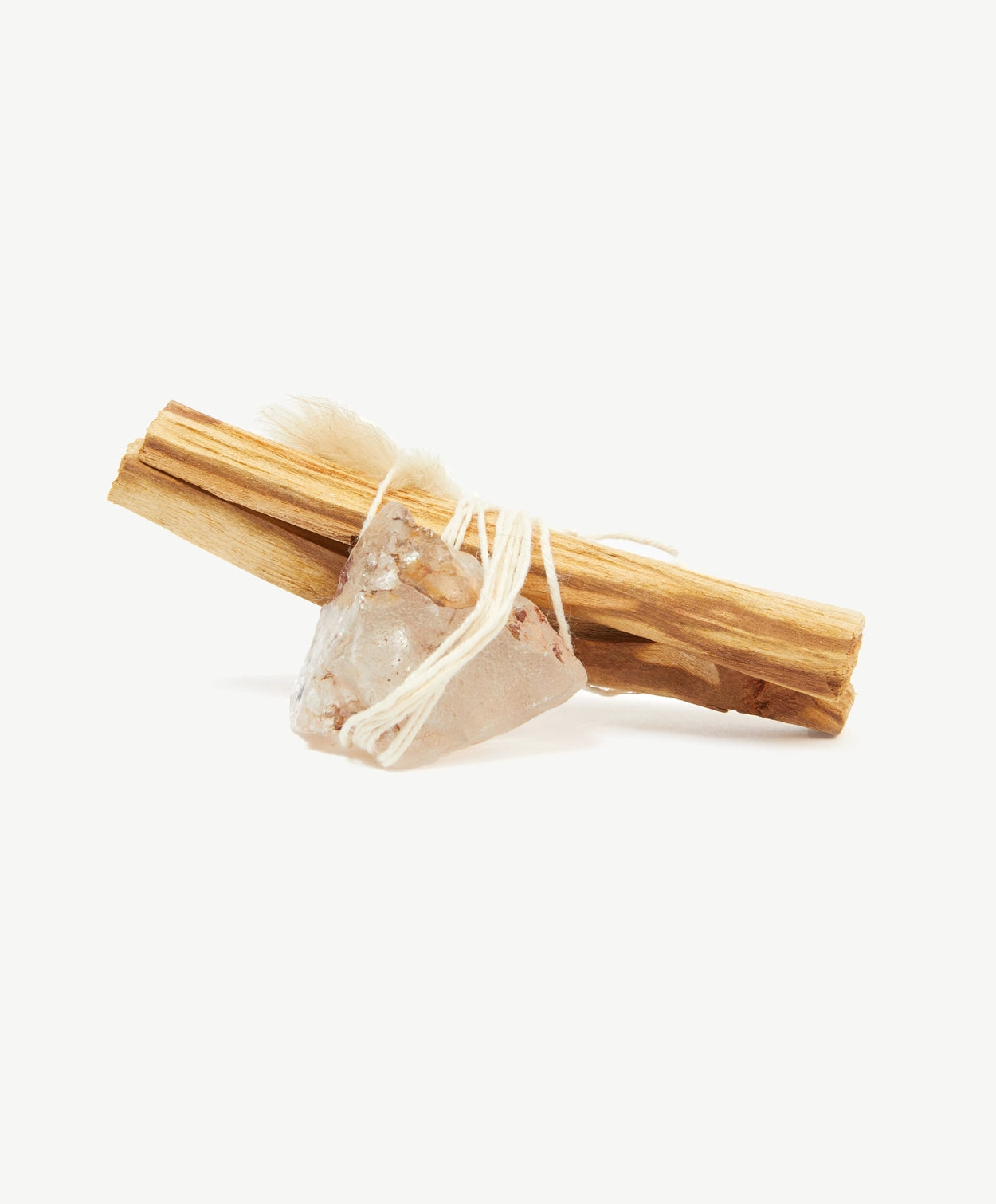 A Palot Santo stick tied to a transparent crystal with white thread string on a white background.