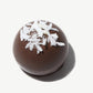 Close-up of a Vosges milk chocolate Wooloomooloo truffle topped with Sri Lankan coconut on a white background.