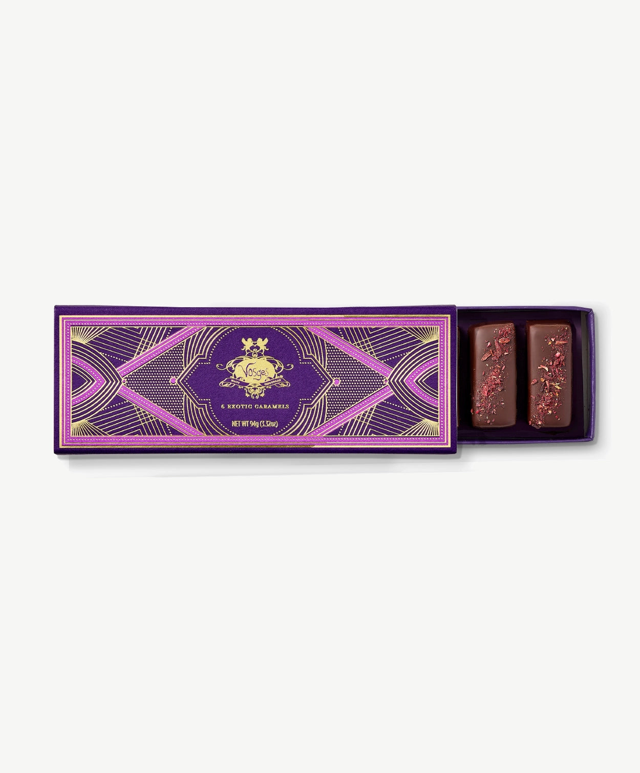 Purple Vosges chocolate box opened revealing two chocolate covered caramels adorned with hibiscus flowers on a grey background.