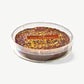 A large chocolate marshmallow disc adorned with gold leaf, pistachios and dried rose petals sit's in a clear case labeled: Lab, Katrina Markoff on a white background. 