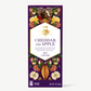 Vosges Cheddar and Apple bar stands upright displaying a purple box wrapper featuring illustrations of fruit and flowers on a grey background.