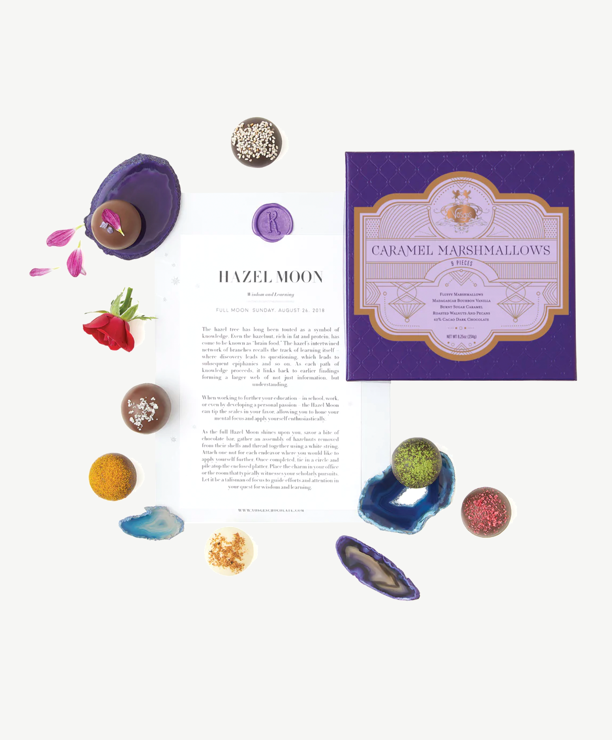 A box of Caramel Marshmallows sits beside several Vosges Chocolate Truffles and brightly colored geodes on a white background.  Central sits a piece of paper reading, "Hazel Moon."