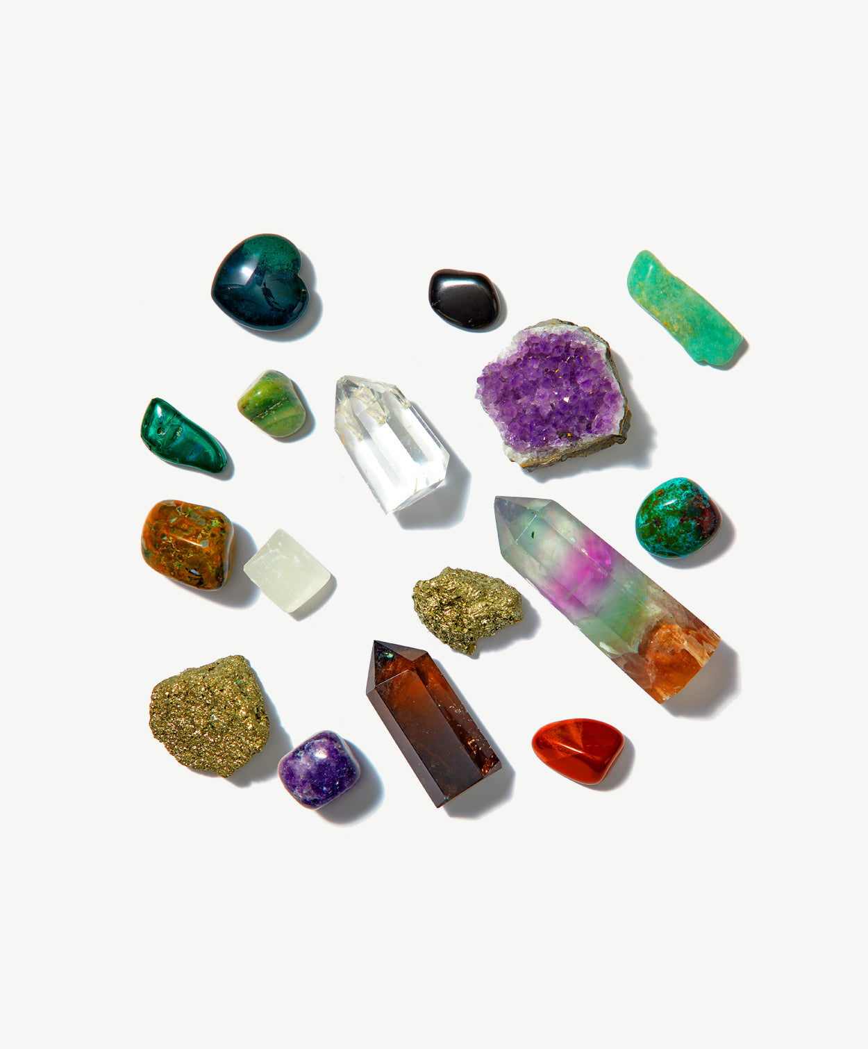 Sixteen brightly colored crystals and precious stones sit scattered on a grey background. 