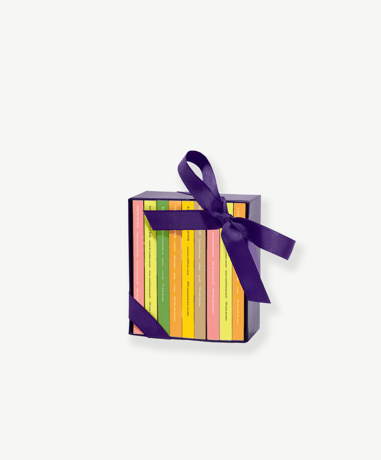 A small chocolate box sits upright displaying 8 miniature chocolate bars in colorful boxes tied with a purple ribbon bow on a grey background.