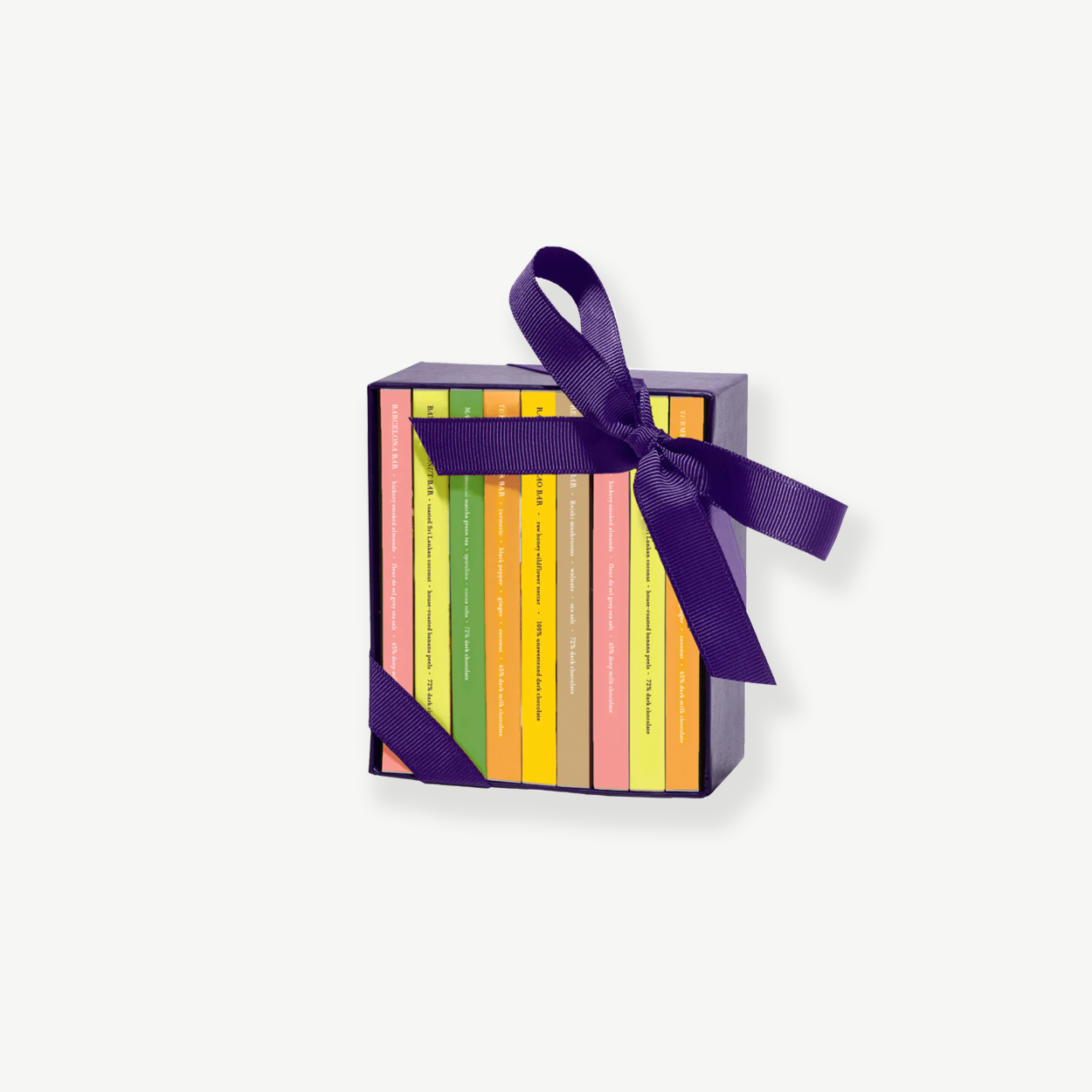 A small chocolate box sits upright displaying 8 miniature chocolate bars in colorful boxes tied with a purple ribbon bow on a grey background.