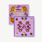 Pale Purple candy box decorated emblazoned in colorful, psychadelic mushroom art sits open displaying a multi-colored collection of chocolate mushroom truffles.  