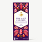 Vosges Pink Salt Caramel bar stands upright displaying a purple box illustrated with pink crystals and fruit on a grey background.