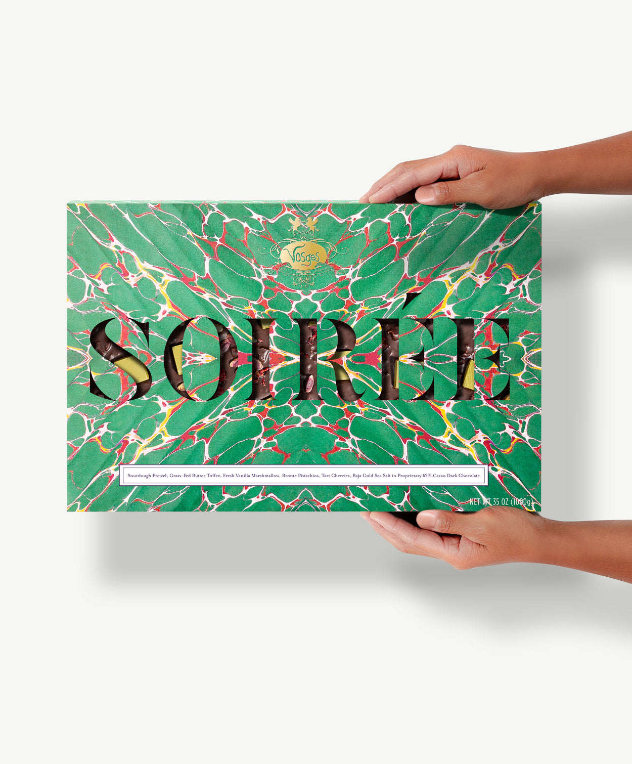 A gigantic two pound Sourdough Pretzel and Toffee Chocolate bar in a green, tie-dyed wrapper reading, "Soiree" held in a Caucasian woman's hands.
