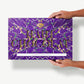 A gigantic two pound super dark gold Leaf Chocolate bar in a purple tie-dyed wrapper reading, "Haut-Chocolat" held in a Caucasian woman's hands.