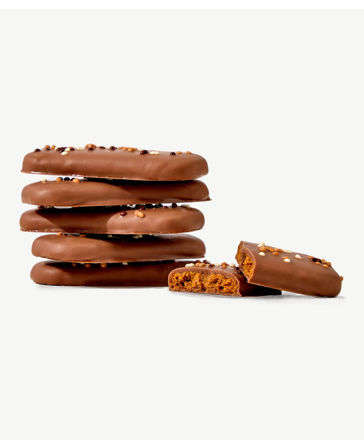 A small stack of Vosges Chocolate dipped Belgian Speculoos Cookies adorned with sprinkles on a white background.