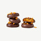 Two small stacks of Vosges Chocolate Dipped Cookies, one cut in half revealing a golden brown cookie adorned with dried persimmon on a grey background.