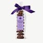 Tall stack of Vosges Chocolate Dipped Persimmon Cookies in a clear plastic wrapper bearing a light purple label, tied with a dark purple bow on a grey background.