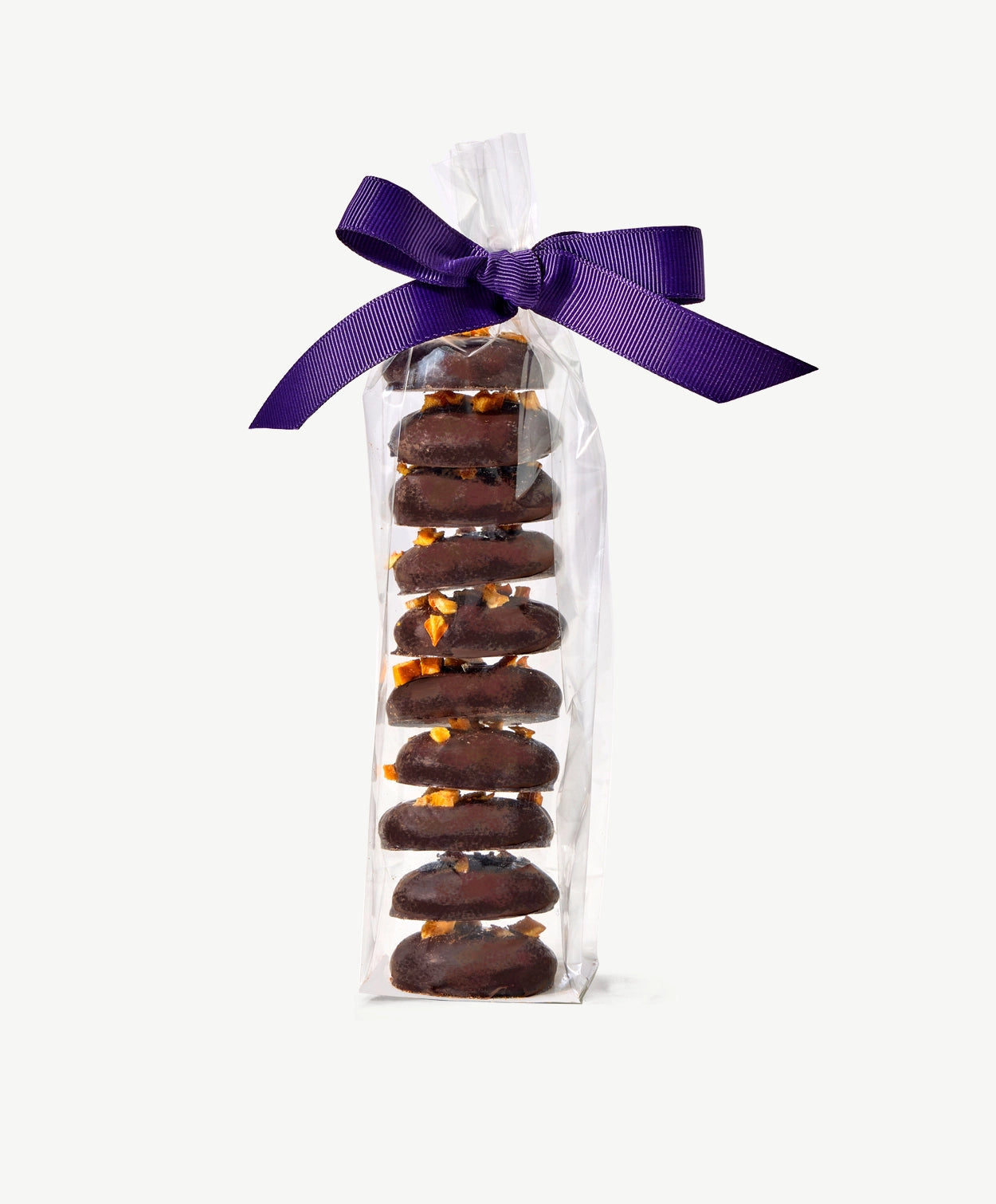 Tall stack of Vosges Chocolate Dipped Cookies topped with dried persimmons, in a clear plastic wrapper tied with a dark purple bow on a grey background.